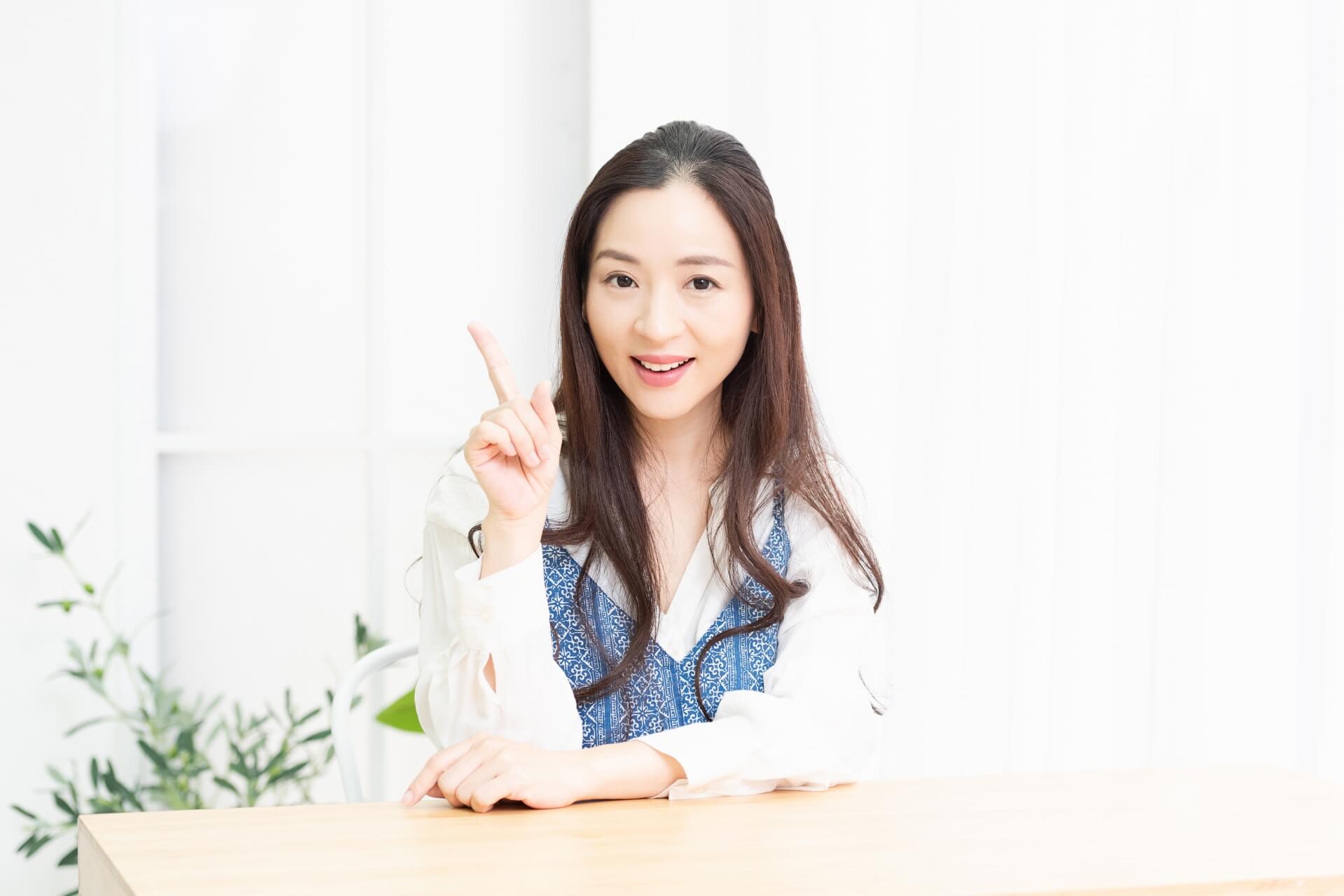 人差し指でポイントを示すリビングで座っている主婦