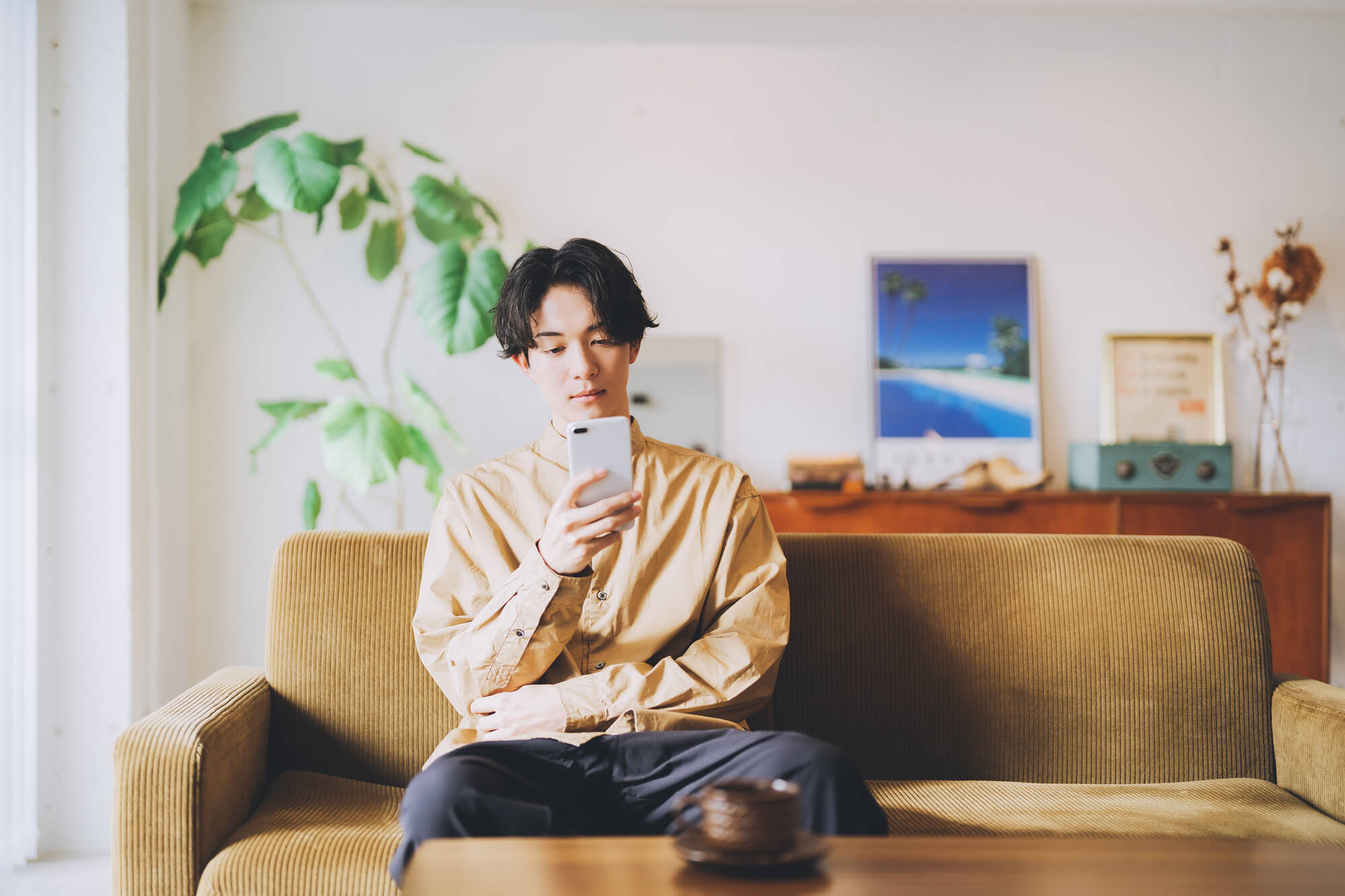 部屋でスマホを見る男性の写真