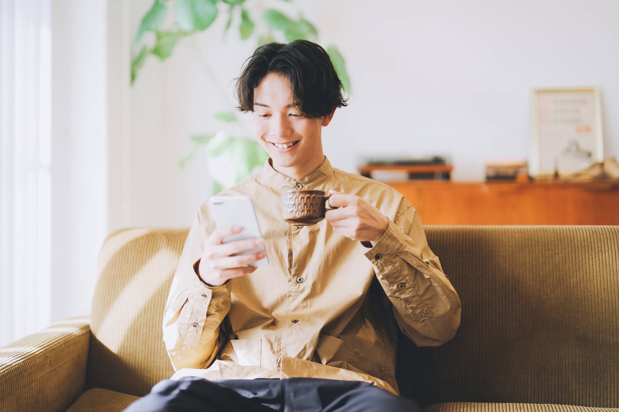 男性がソファで携帯を見ている