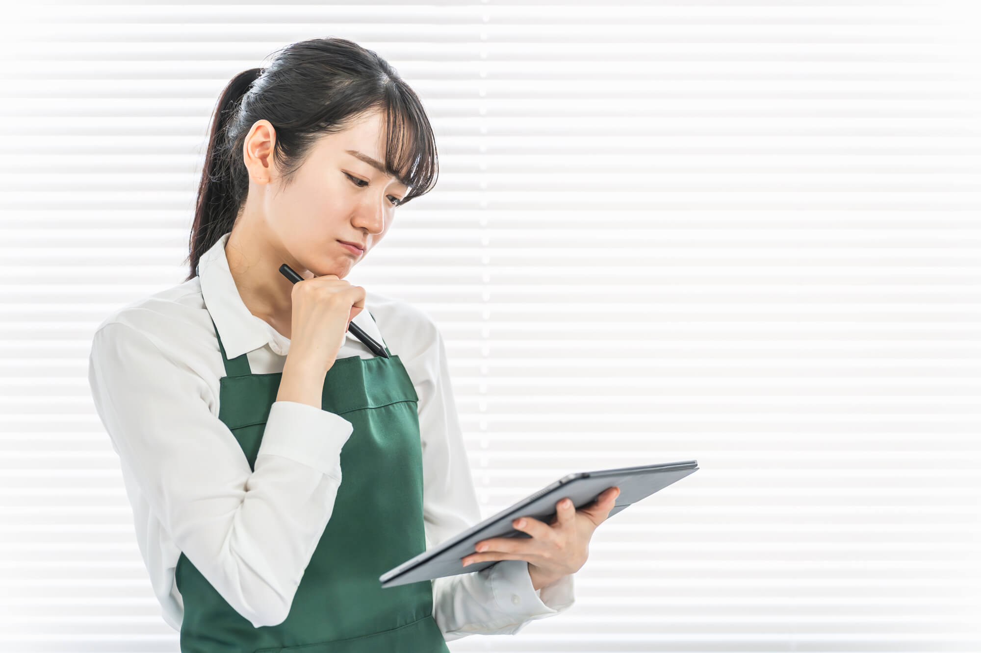 タブレットの画面を見て悩むスーパーの店員