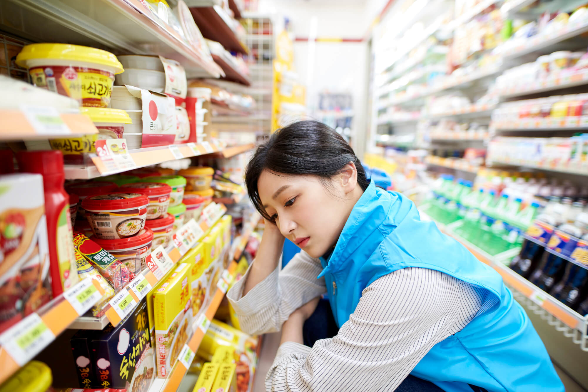 商品棚を見て悩むスーパーのチーフ