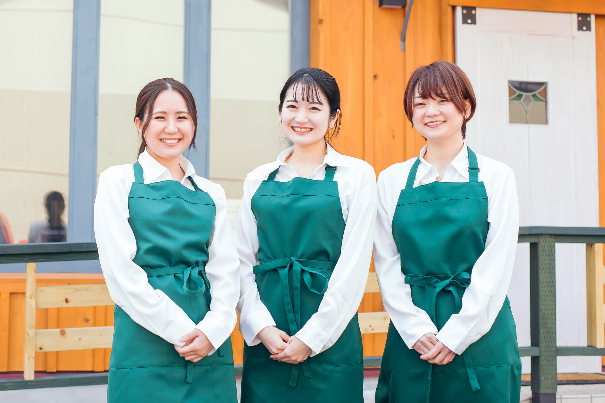 笑顔で並ぶ3人のスーパーの店員